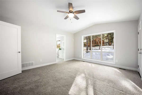 an empty room with chandelier fan and windows