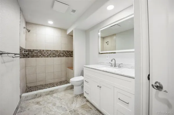 a bathroom with a granite countertop sink toilet a mirror a vanity and shower