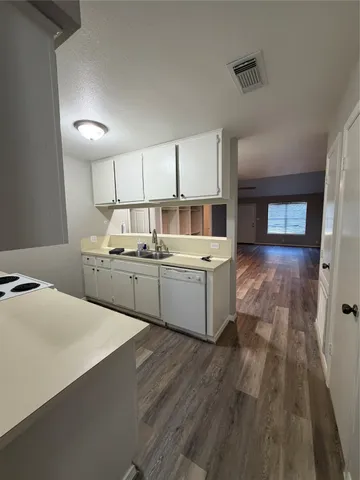 a kitchen with a sink cabinets and wooden floor