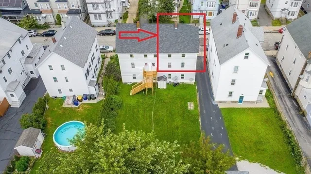 an aerial view of residential houses with outdoor space and parking