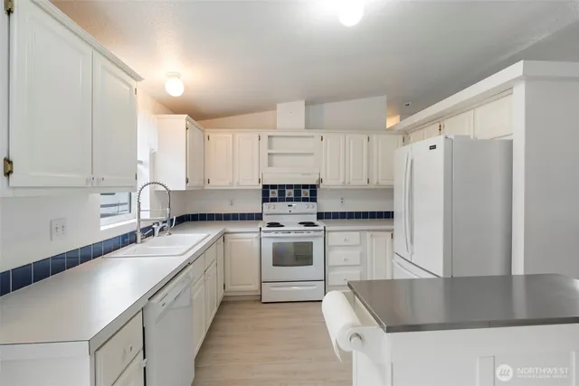 a kitchen with granite countertop a sink stainless steel appliances and white cabinets