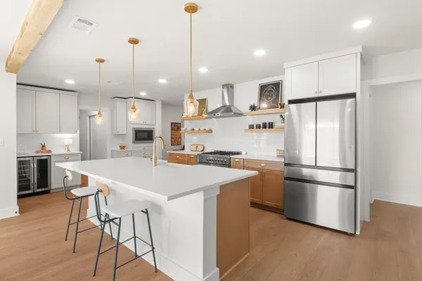 a kitchen with stainless steel appliances granite countertop a refrigerator a sink dishwasher a stove and a refrigerator with wooden floor