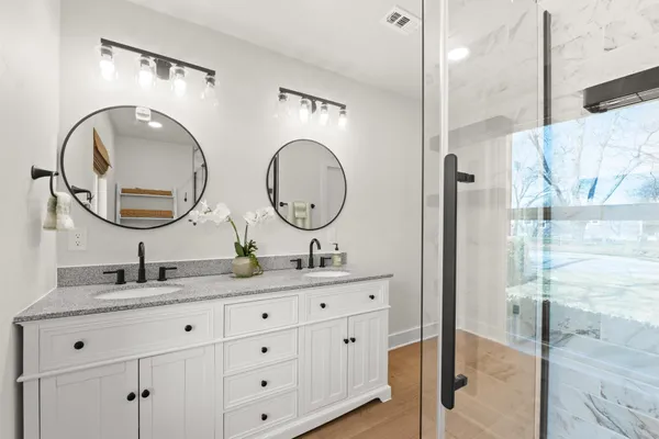 a bathroom with a granite countertop double vanity sink and a mirror