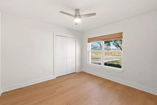 an empty room with chandelier fan and windows