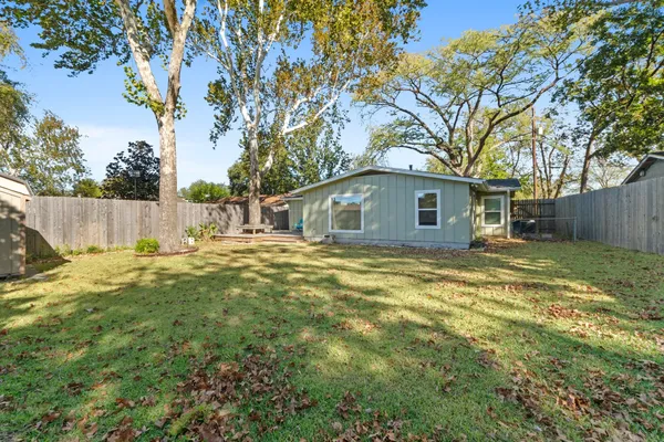 a backyard of a house with large trees and brick walls