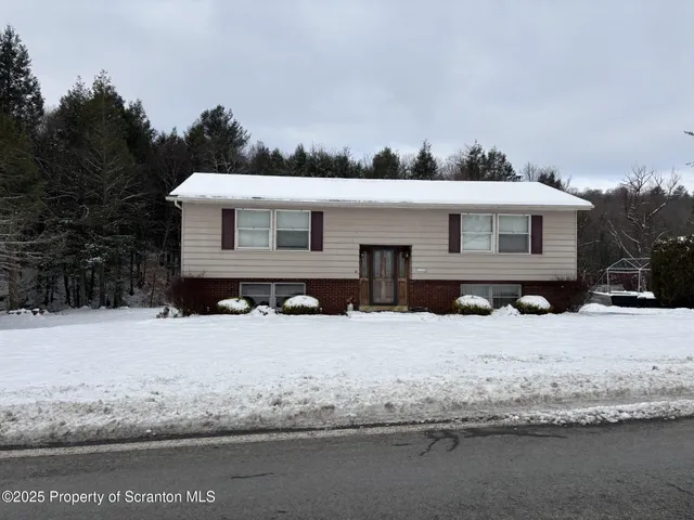 a front view of a house with a yard covered in snow