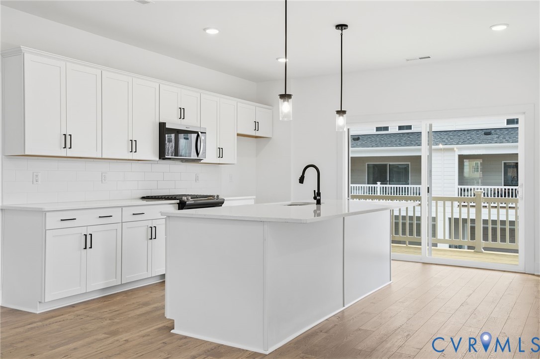 12016 Afternoon Path Henrico, VA 23233 - Photo 11 of 36 a kitchen with stainless steel appliances granite countertop a stove a sink and white cabinets with wooden floor