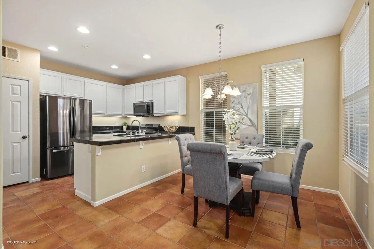 1685 Avery Road San Marcos, CA 92078 - Photo 9 of 26 a kitchen with stainless steel appliances granite countertop a refrigerator a stove a sink dishwasher a dining table and chairs with wooden floor