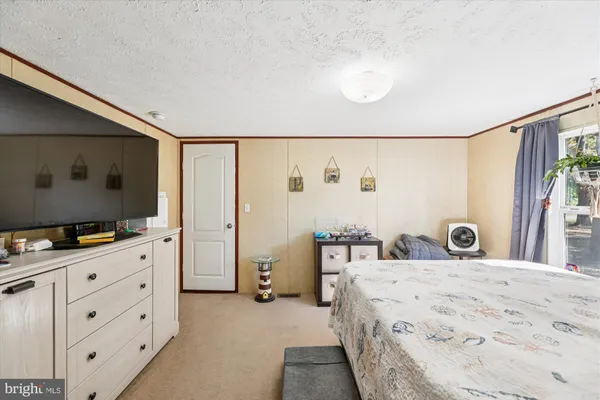 a bedroom with a bed and a flat tv screen on dresser
