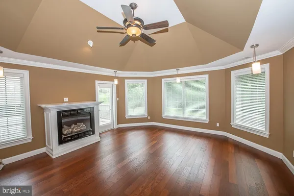 a view of an empty room with wooden floor fireplace and a window