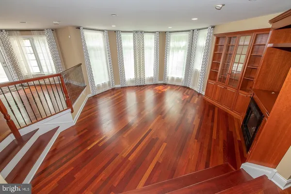a view of an empty room with wooden floor and staircase