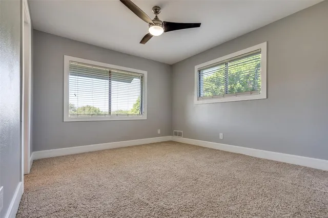 an empty room with a window and a ceiling fan