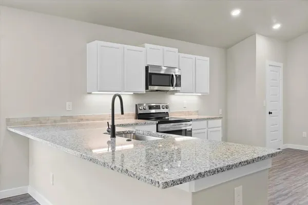 a kitchen with granite countertop a sink a stove and a microwave