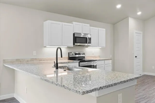 a kitchen with granite countertop a sink a stove and a microwave