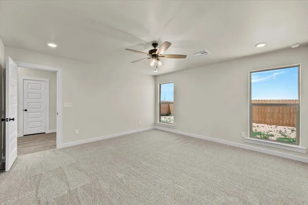 an empty room with chandelier fan and windows