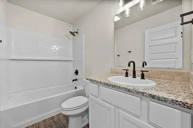 a bathroom with a granite countertop toilet sink and mirror