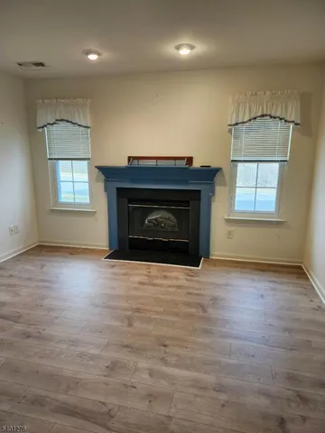 an empty room with wooden floor fireplace and windows