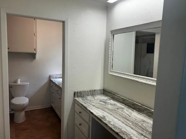 a bathroom with a granite countertop sink and a toilet
