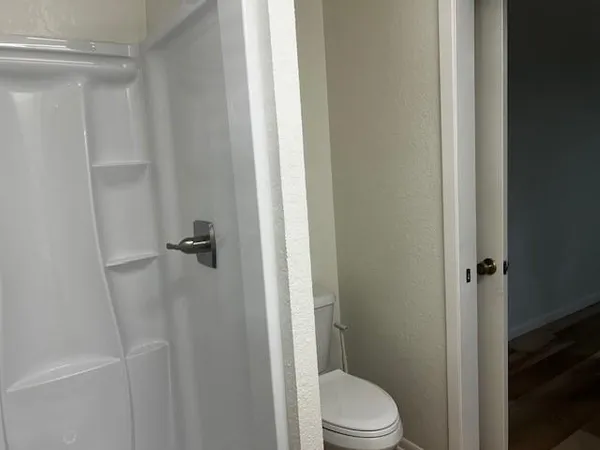 a white toilet sitting next to a shower