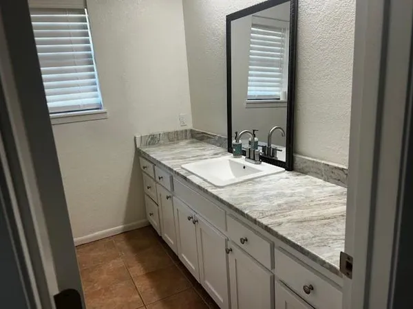 a bathroom with a granite countertop sink and a window