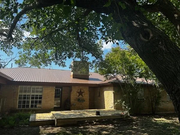 a view of a white house next to a yard with large trees