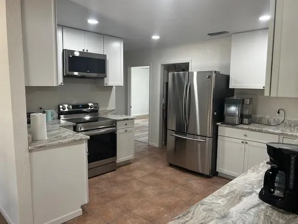 a kitchen with stainless steel appliances granite countertop a refrigerator stove a sink and a microwave