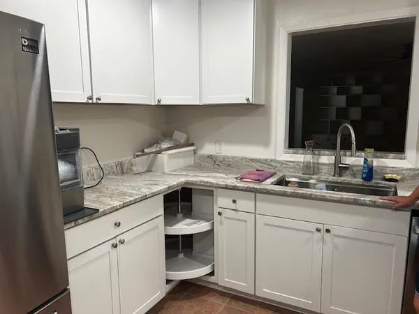 a kitchen with granite countertop white cabinets and a sink