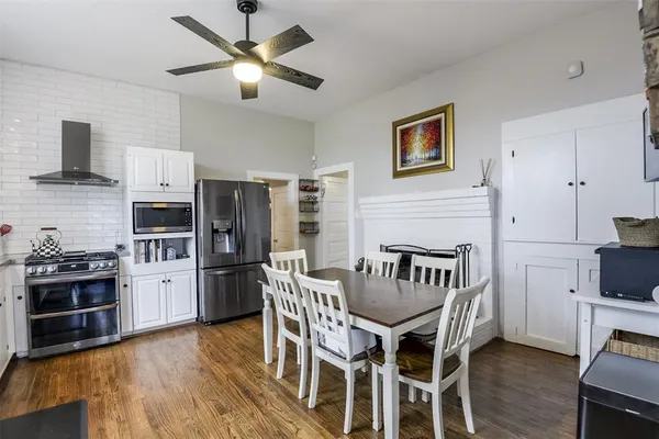 a kitchen with stainless steel appliances granite countertop a stove a refrigerator a kitchen island a dining table and chairs