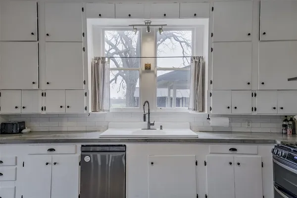 a kitchen with granite countertop white cabinets and a sink