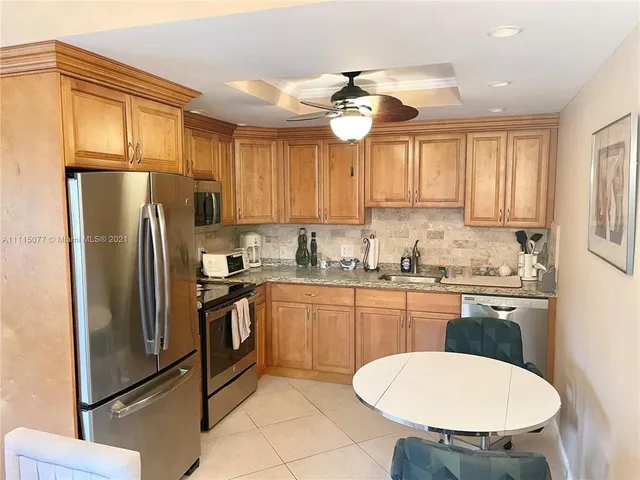 a kitchen with stainless steel appliances granite countertop a sink a stove a refrigerator cabinets and dining table