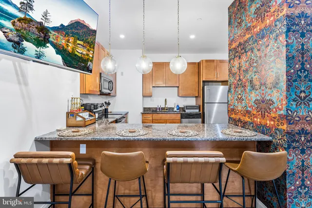 a kitchen with stainless steel appliances kitchen island granite countertop a sink and a white cabinets