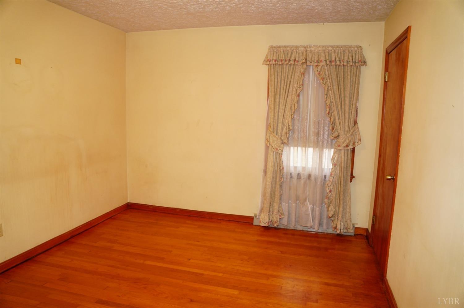 2106 Railview Road Gladys, VA 24554 - Photo 9 of 20 an empty room with wooden floor and windows with curtains