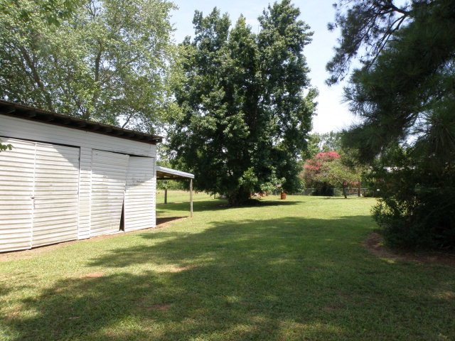373 Greene Settlement Road Gray, GA 31032 - Photo 21 of 34 a yellow house in middle of a field with trees in the background