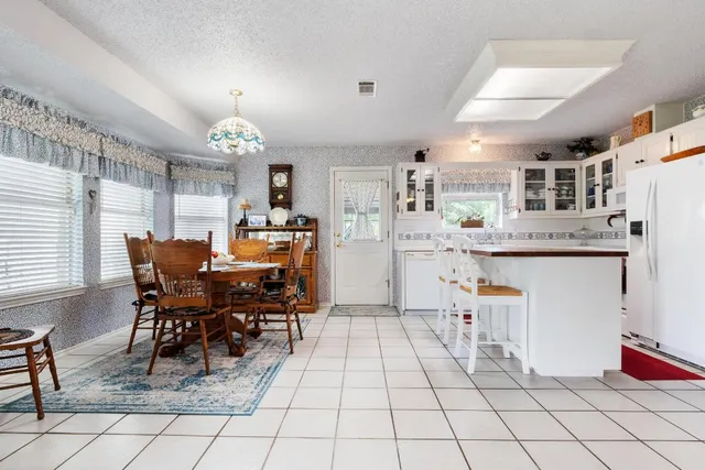a kitchen with stainless steel appliances kitchen island granite countertop dining table chairs cabinets and a window