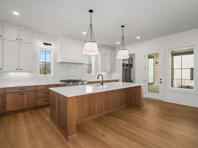 a large kitchen with kitchen island a stove a sink a center island and a wooden floor