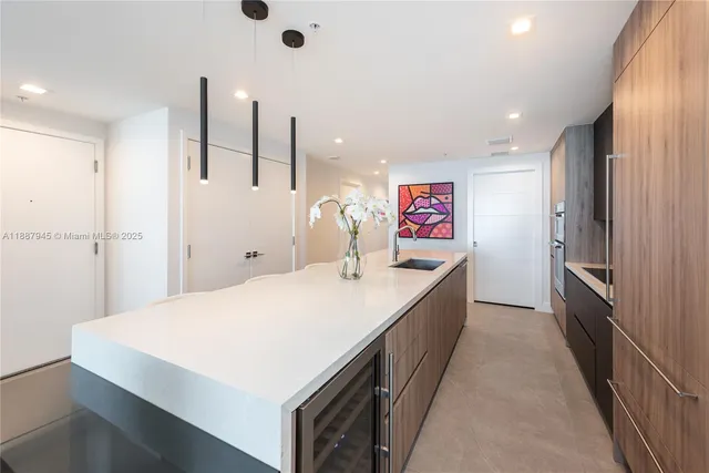 a large kitchen with a large counter top a stove a sink and a refrigerator