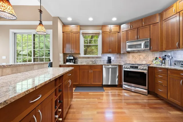 a kitchen with stainless steel appliances granite countertop a stove and a wooden floors