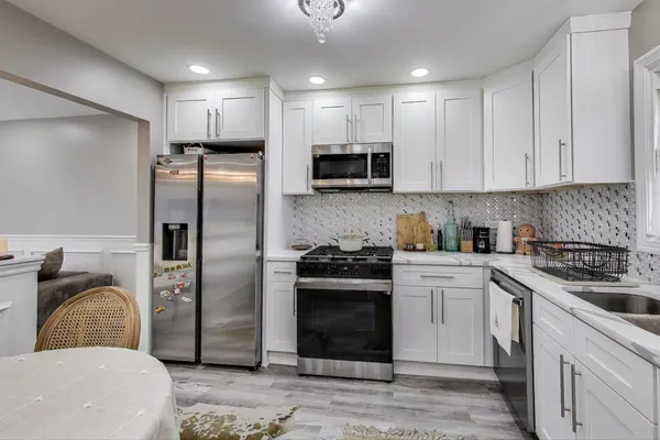 a kitchen with stainless steel appliances granite countertop a refrigerator a stove a sink and a microwave