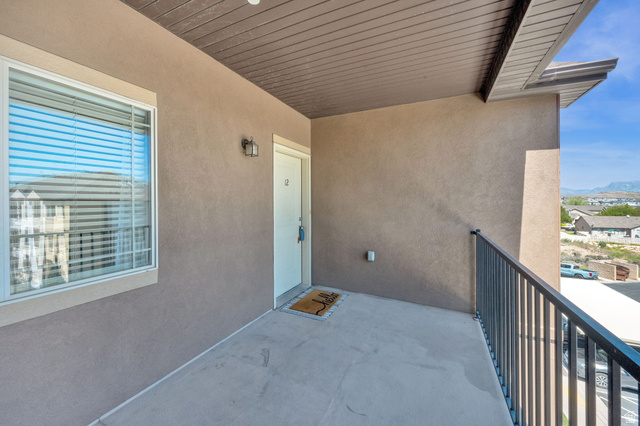 8215 Clear Rock Road, Unit 12 Eagle Mountain, UT 84005 - Photo 37 of 38 Private concrete balcony with stucco exterior, dark metal railing, and soffit ceiling