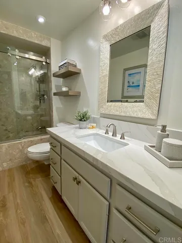 a bathroom with a granite countertop sink a toilet a mirror and bathtub