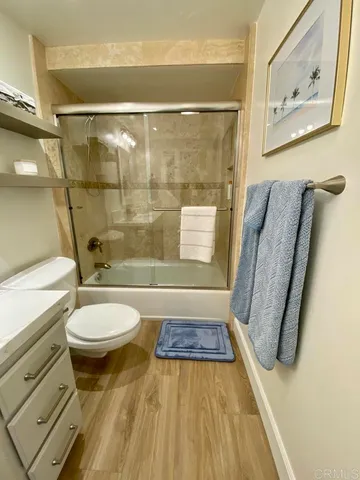 a bathroom with a granite countertop bathtub shower sink vanity and toilet