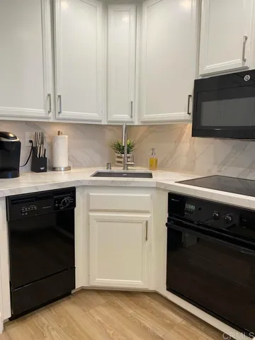 a kitchen with granite countertop white cabinets and black appliances
