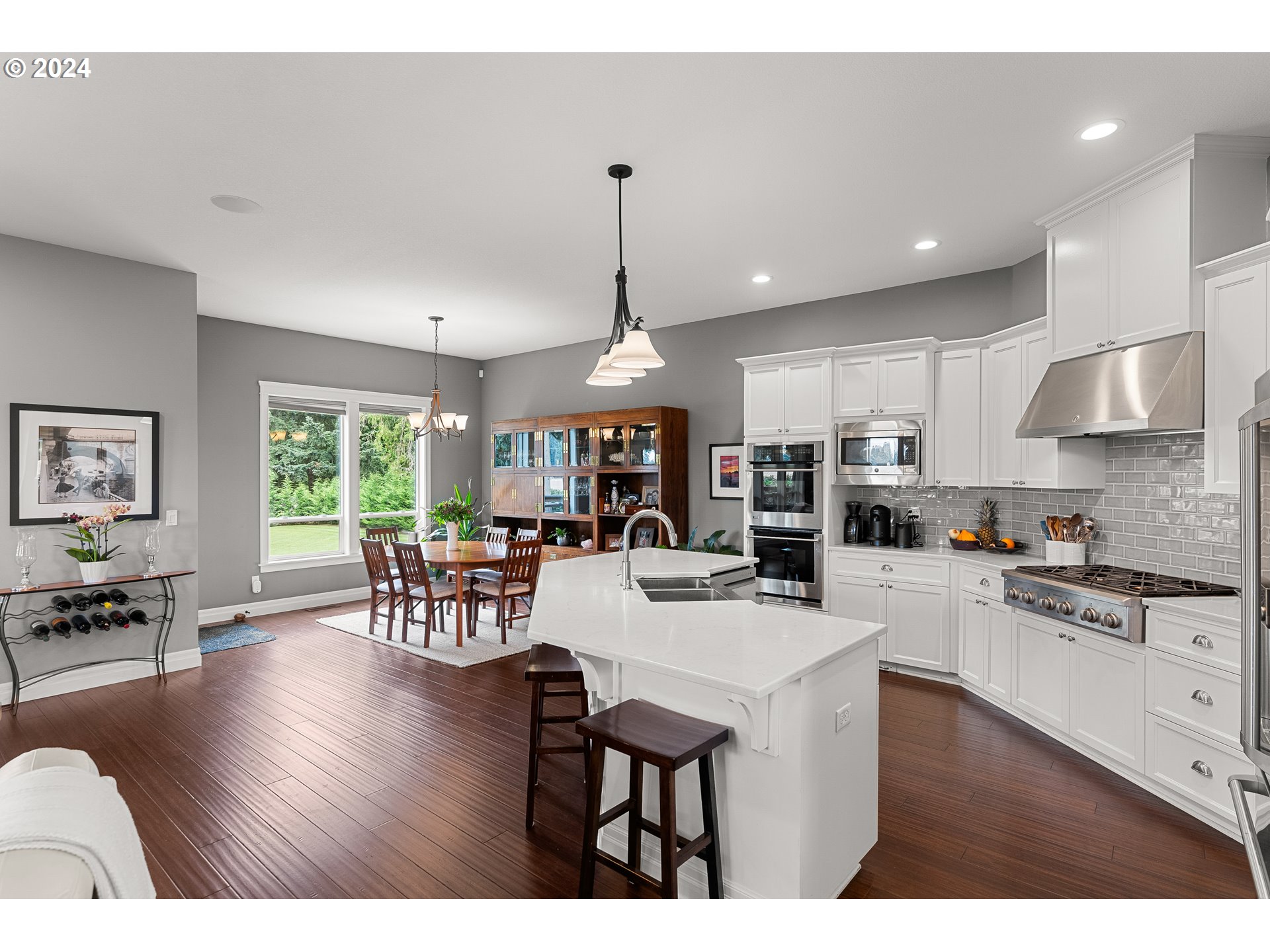 25595 South Rhoten Road Aurora, OR 97002 - Photo 15 of 48 a kitchen with stainless steel appliances granite countertop a stove a refrigerator a kitchen island a dining table and chairs with wooden floor