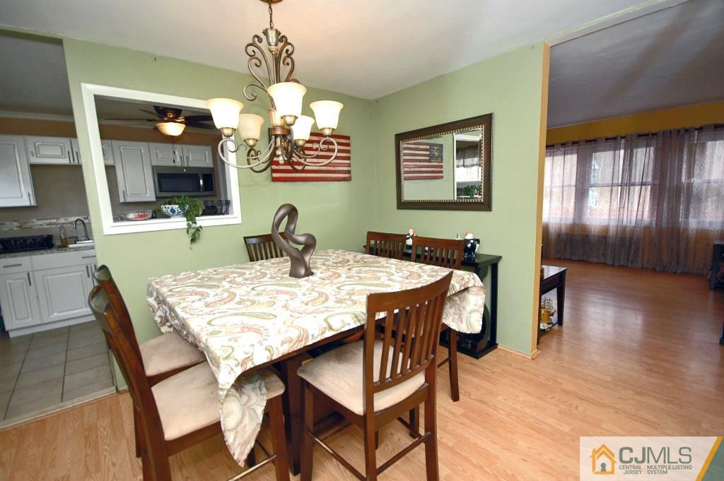 3066 Cheesequake Road Old Bridge, NJ 08859 - Photo 8 of 24 a dining room with wooden floor a chandelier a wooden table and chairs
