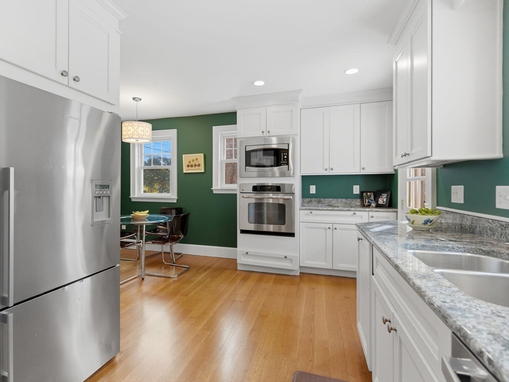 24 Blake Road Brookline, MA 02445 - Photo 10 of 40 a kitchen with granite countertop a refrigerator a stove top oven a sink dishwasher and white cabinets with wooden floor