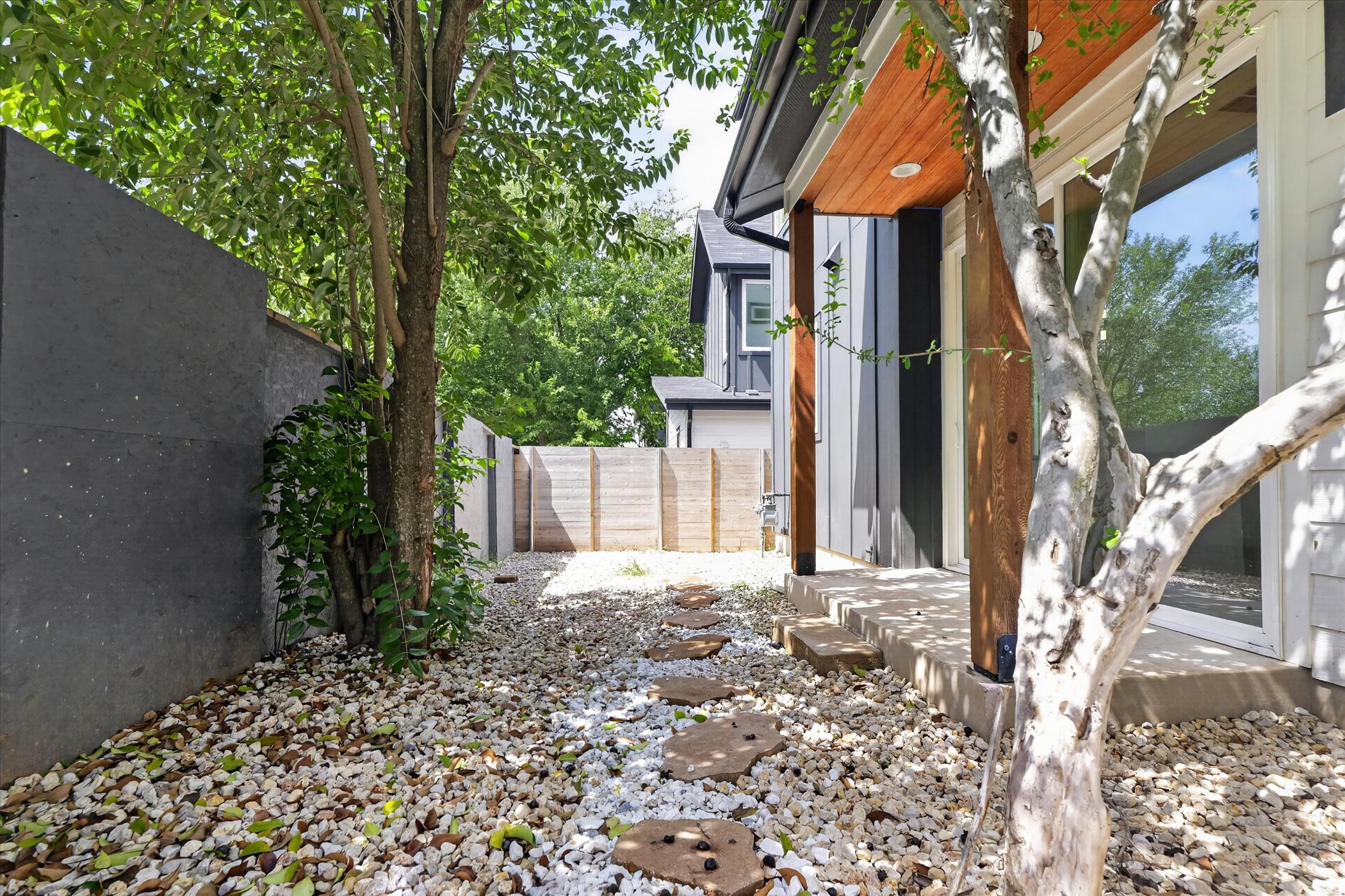 5305 Ledesma Road, Unit 1 Austin, TX 78721 - Photo 27 of 29 A tranquil gravel path with stepping stones leads to the private yard, bordered by mature trees and contemporary fencing.