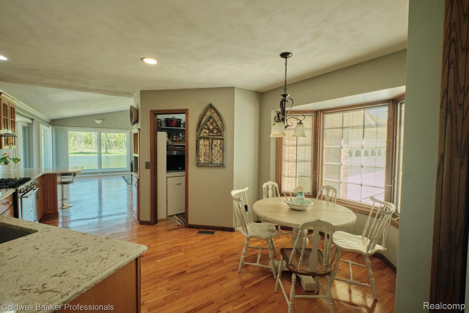 6464 Ferden Road Chesaning, MI 48616 - Photo 9 of 23 Dining area with vaulted ceiling, light wood-style floors, and a chandelier