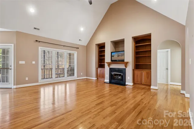 a view of an empty room with wooden floor fireplace and a window