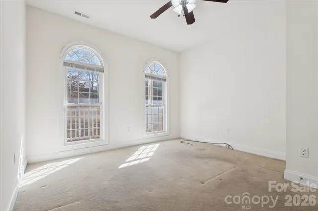 an empty room with windows and fan