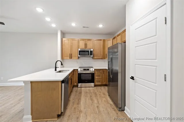 a kitchen with stainless steel appliances granite countertop a refrigerator a sink a stove and a refrigerator with wooden floor